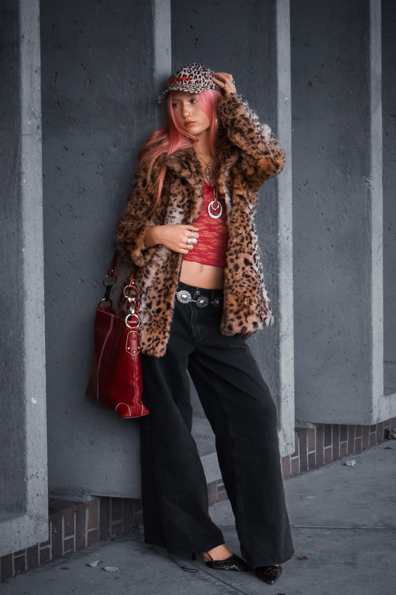 Model in leopard coat standing by a concrete wall in grayscale