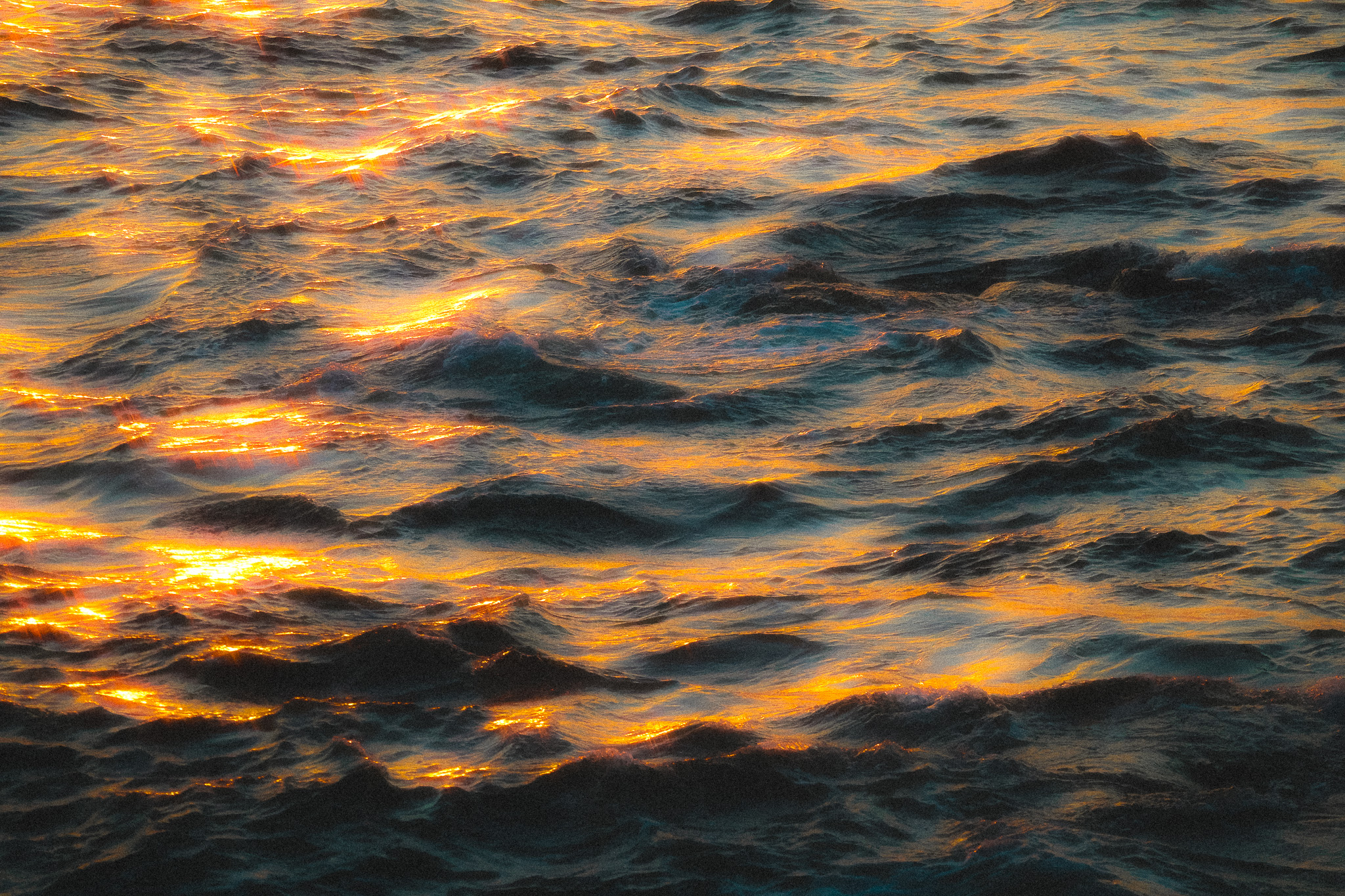 Golden sunlight reflecting across ocean water in grayscale