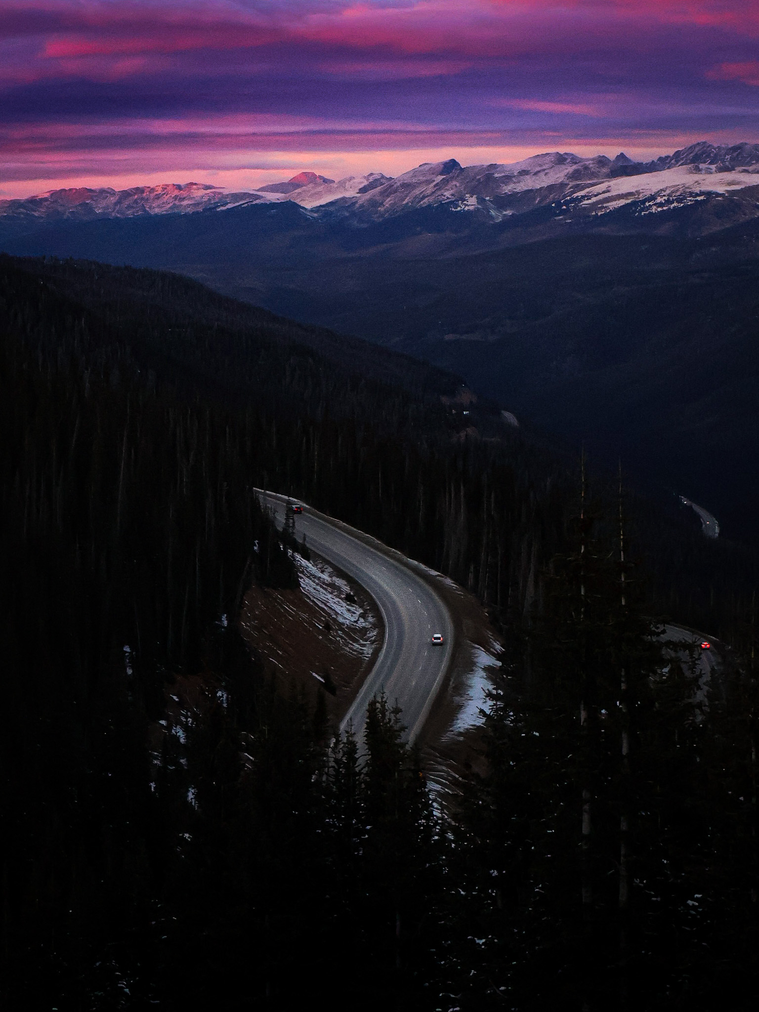Mountain road winding through dark hills at dusk in grayscale