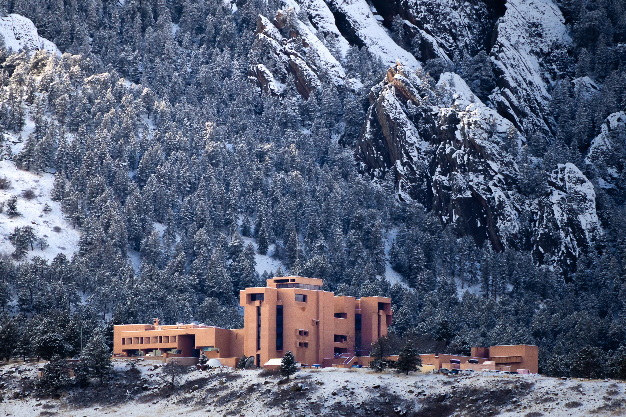 NCAR building below snowy Colorado Flatirons in grayscale