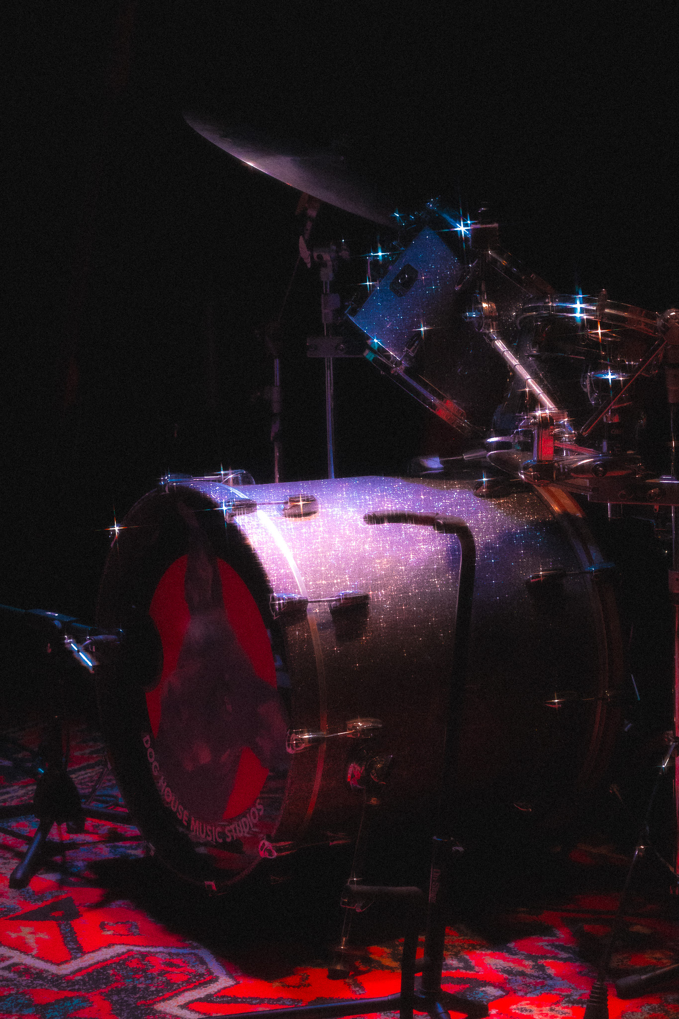 Drum kit lit by red and blue stage lights in grayscale
