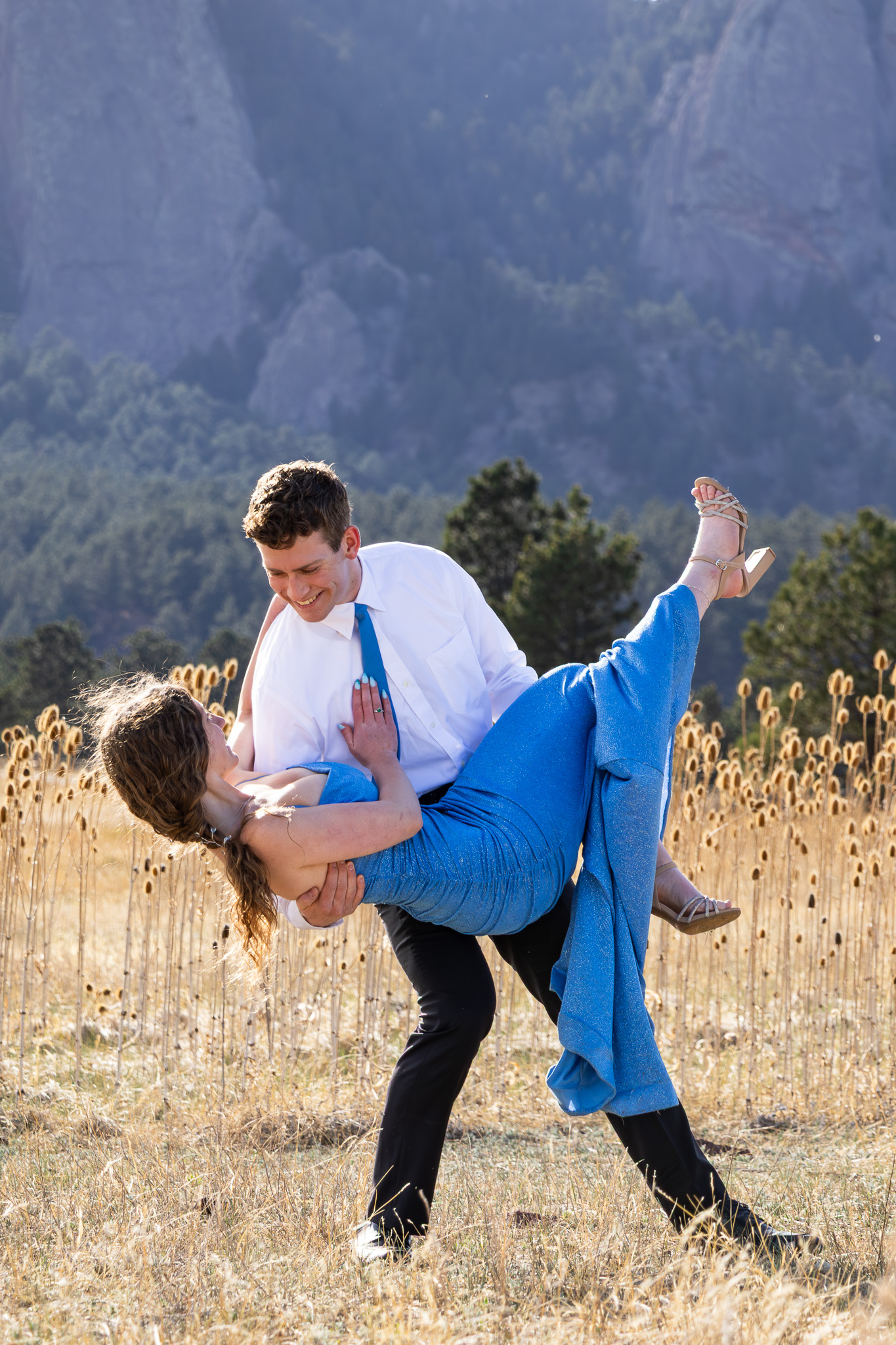 Couple posing playfully in a mountain field in grayscale