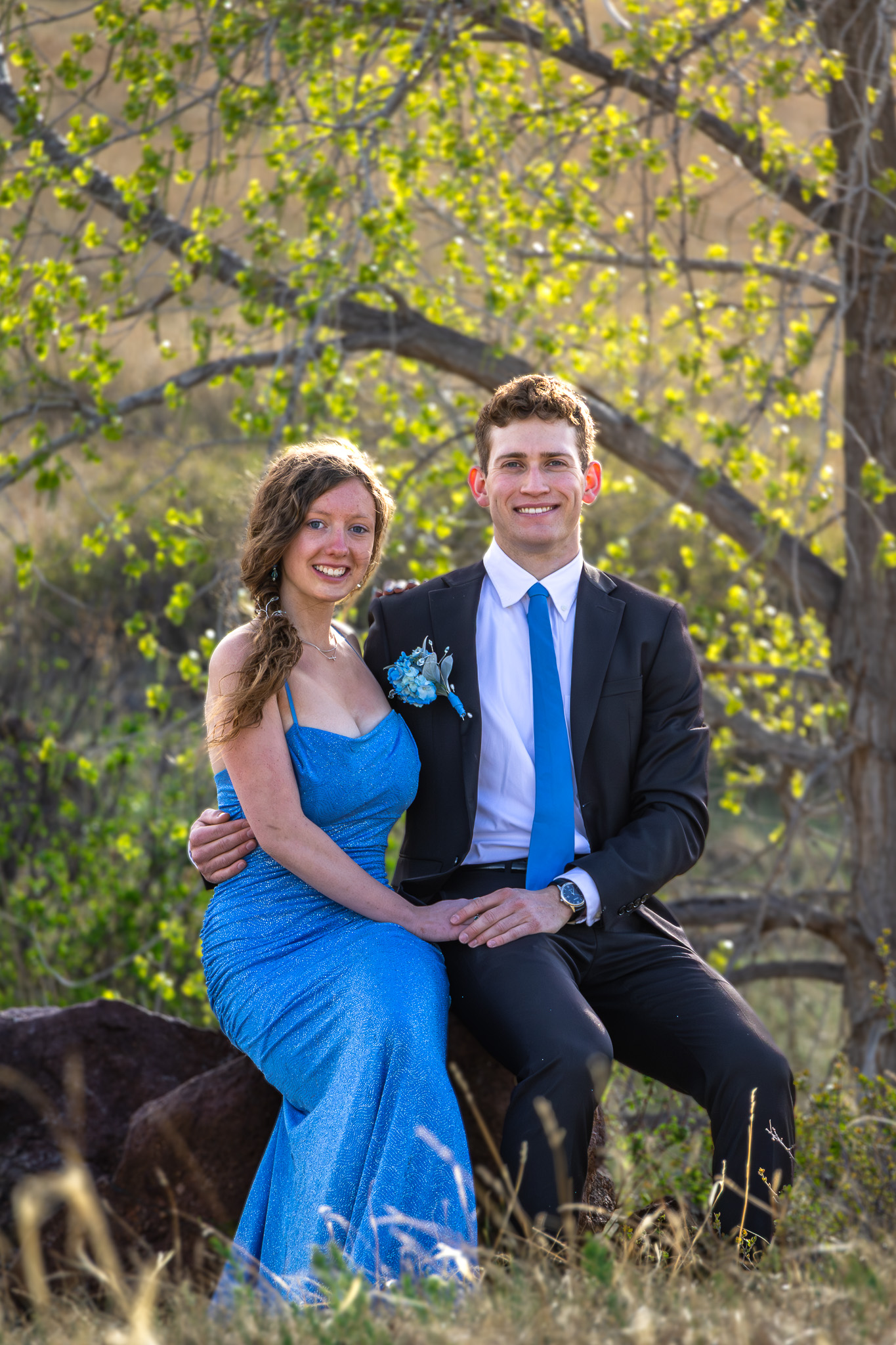 Couple in formal clothes seated under autumn trees in grayscale