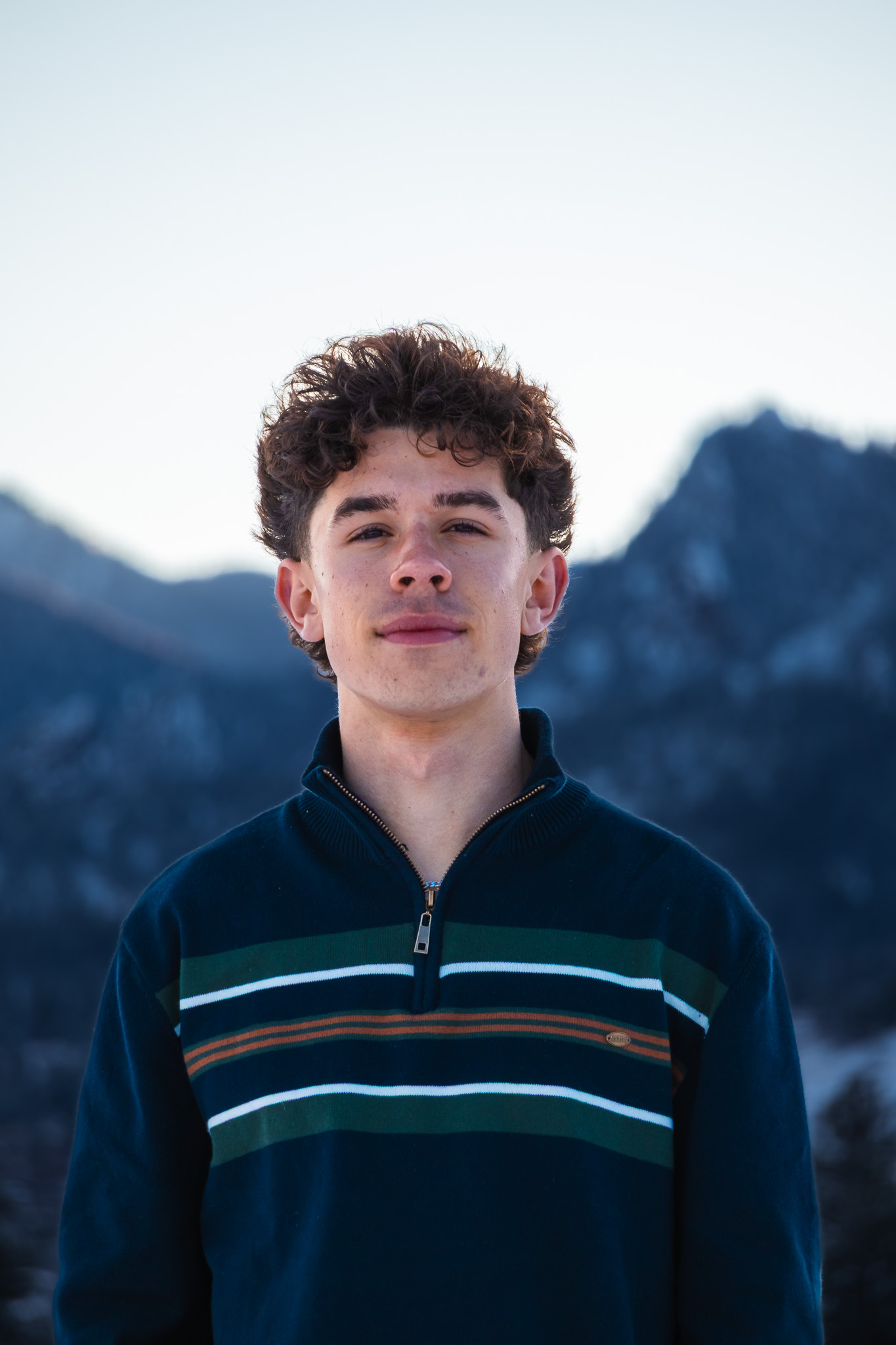 Portrait of a young man in a striped sweater with mountains behind him in grayscale