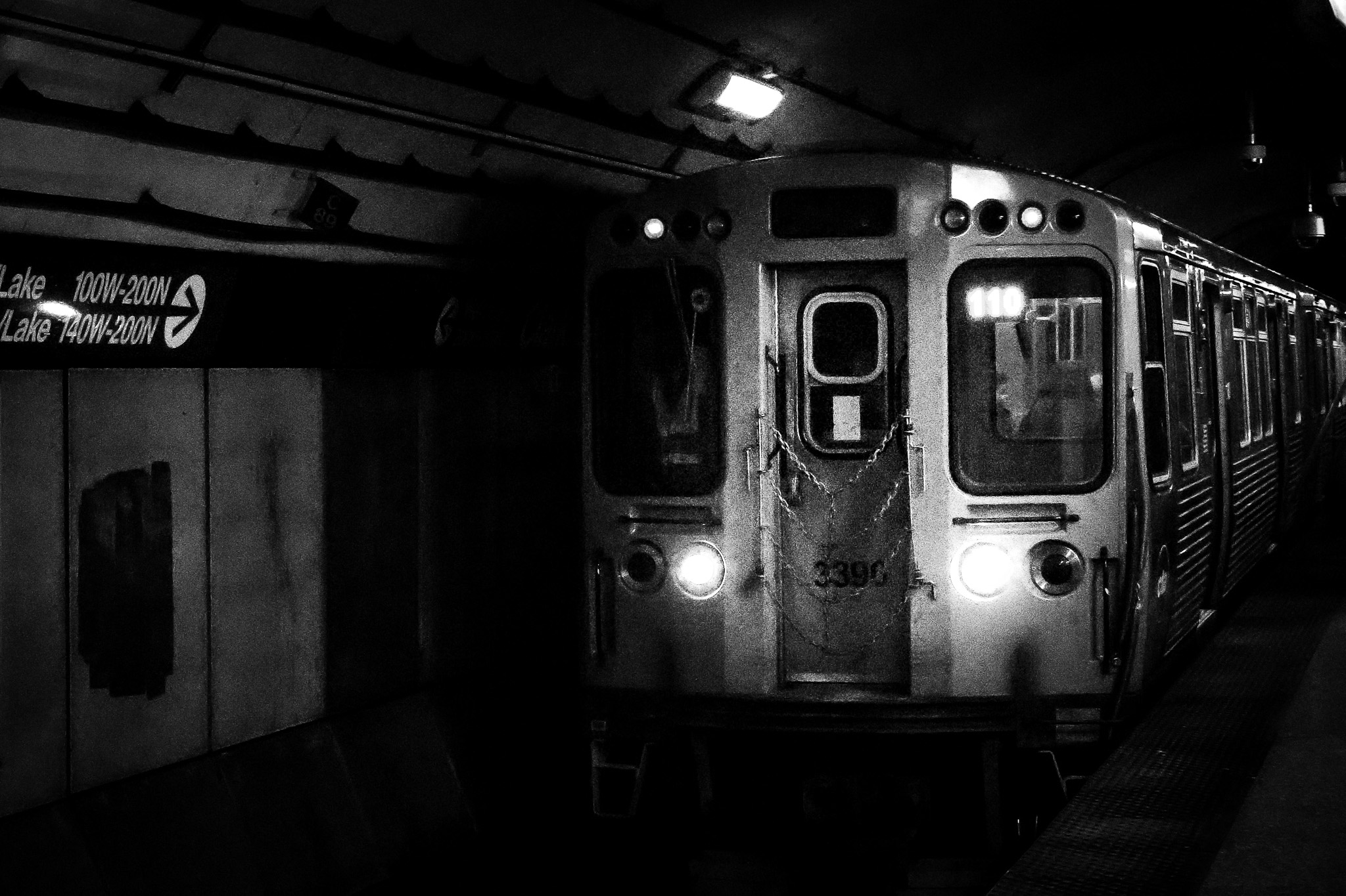 Black and white subway train pulling into a station in grayscale