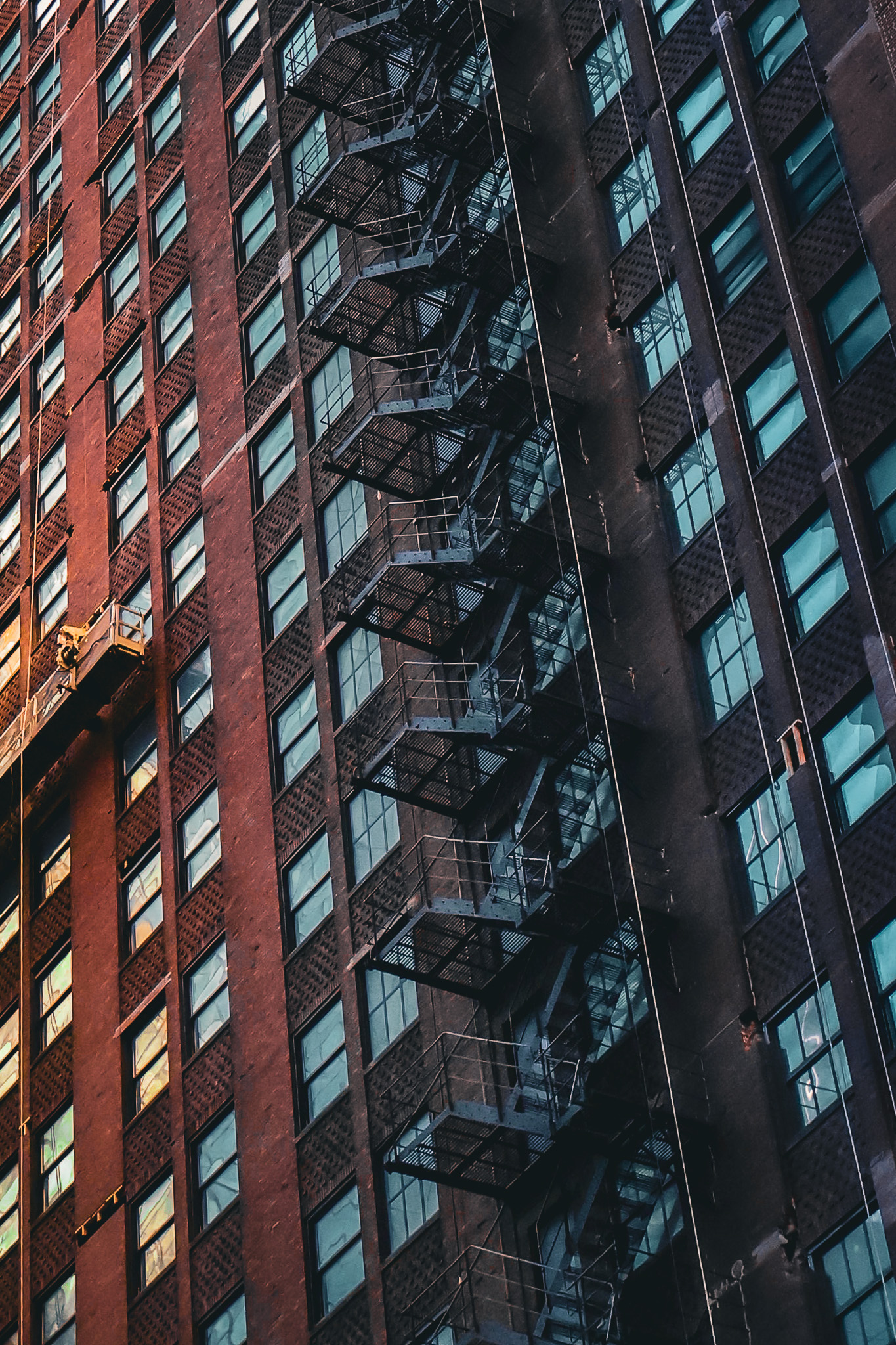 Red brick high-rise with fire escapes in grayscale