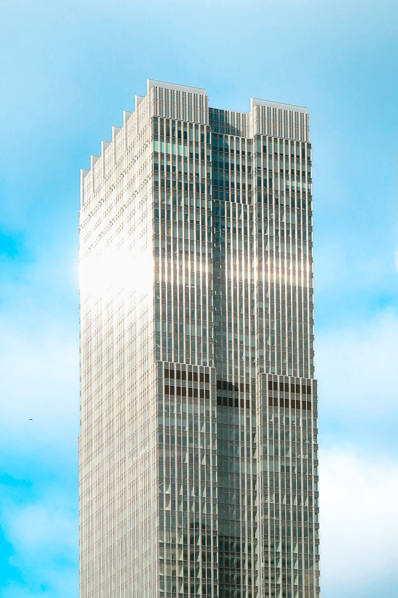 Tall glass tower against a blue sky in grayscale